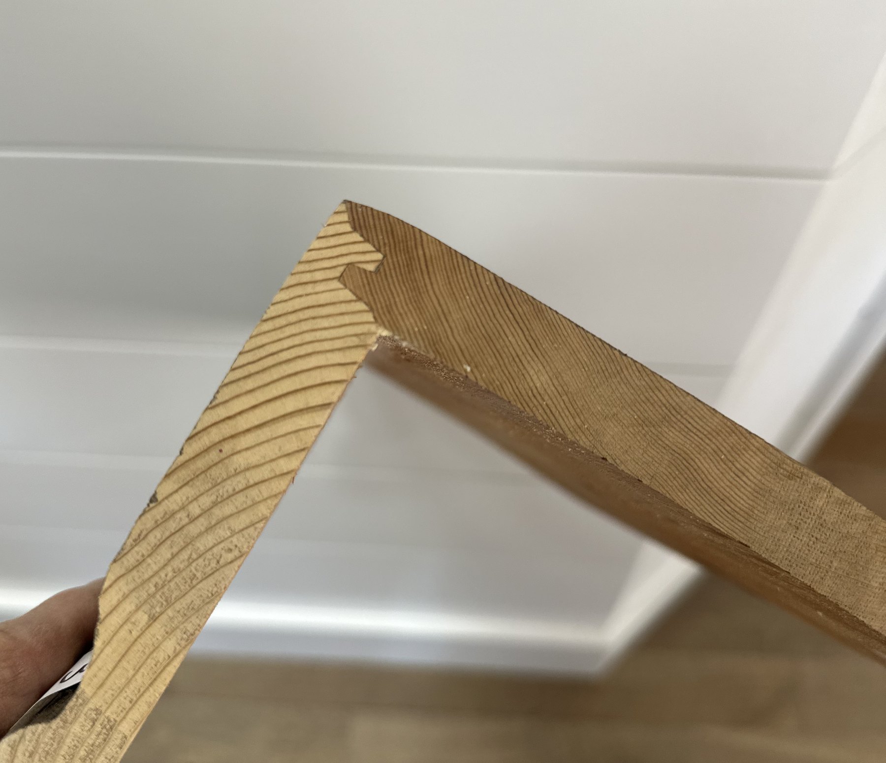 Miter-lock joint corner sample held in hand, showing the chamfered seam and interlocking tooth