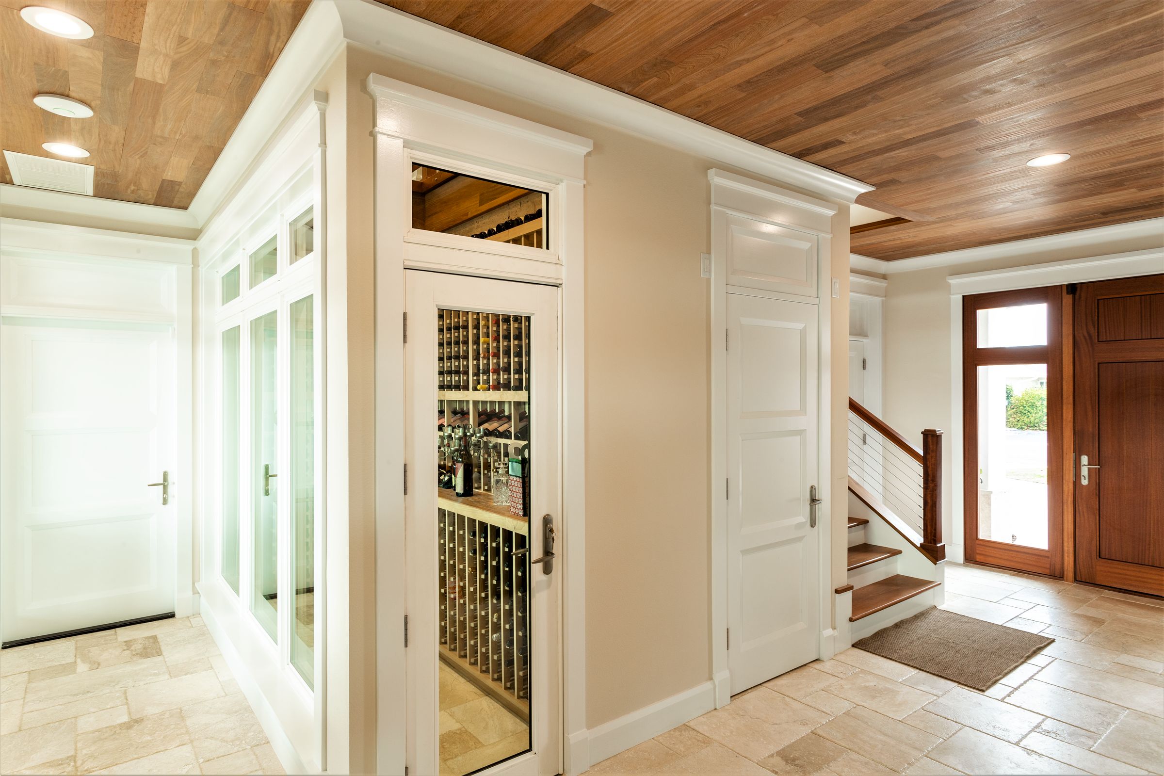 Entry hall with a wood ceiling, cased interior doors with transoms, wood stair treads, and a wood entry door